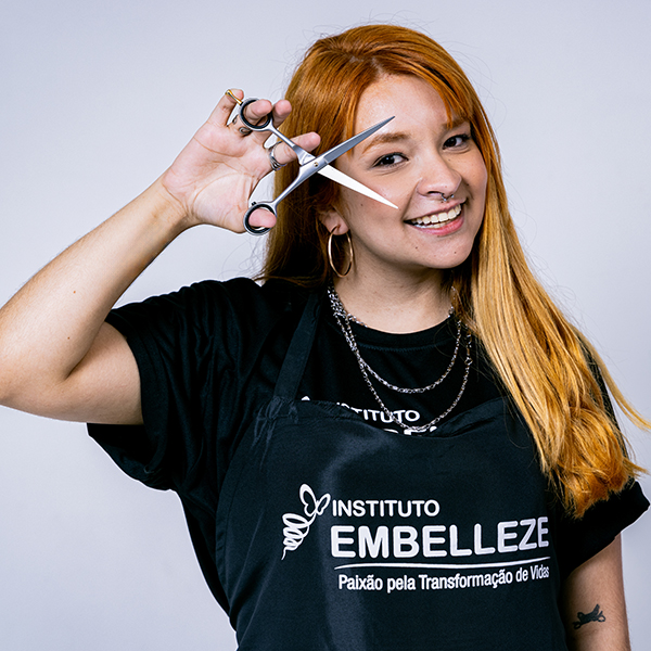 Aluna de cabeleireiro realizando corte em cliente